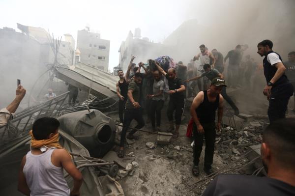 Palestinians remove a dead body from the rubble of a building after an Israeli airstrike.